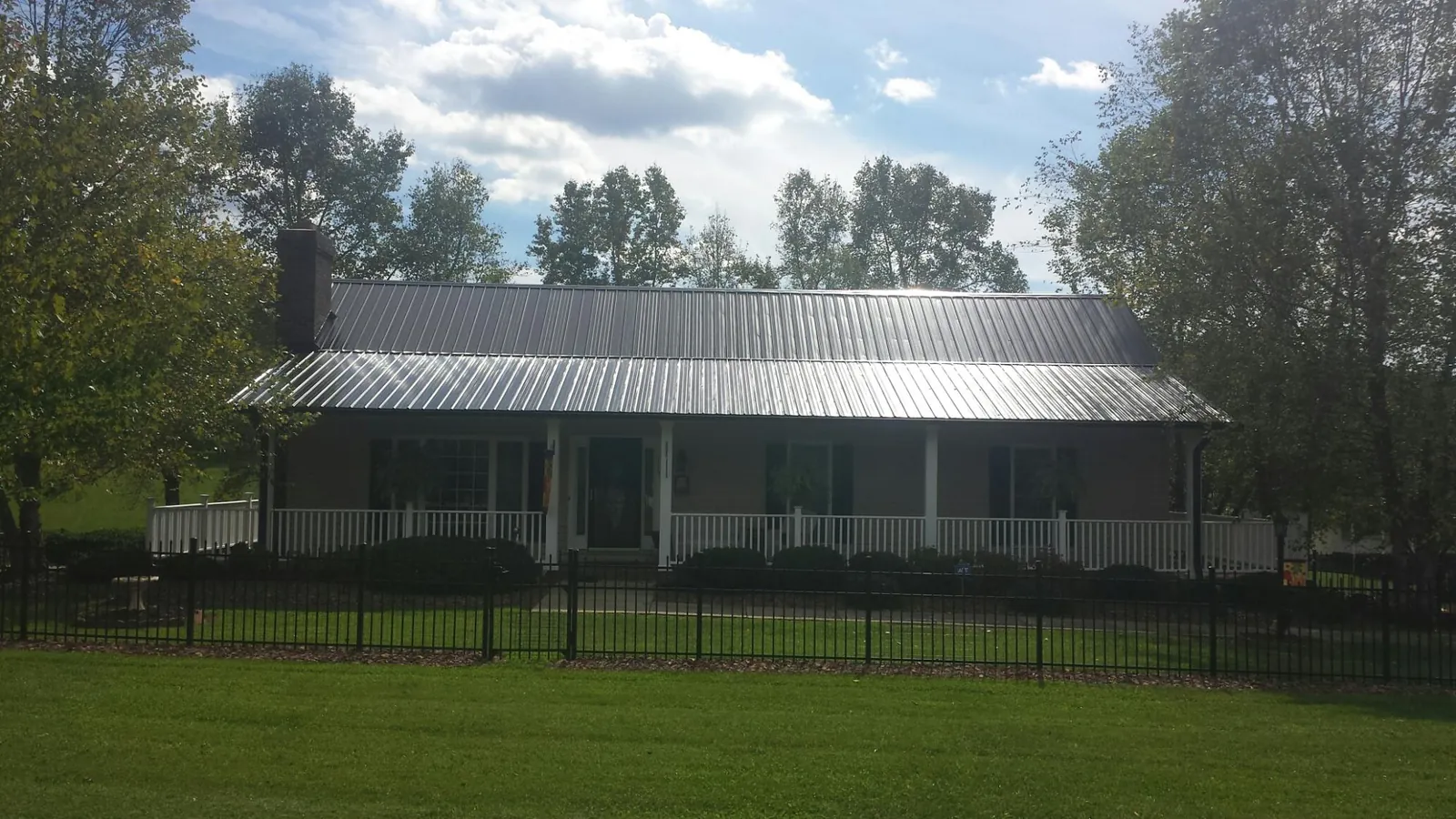 Gray metal roof on a brick ranch with a full width front porch — Gutter Guard Installation work by our crew in West Point